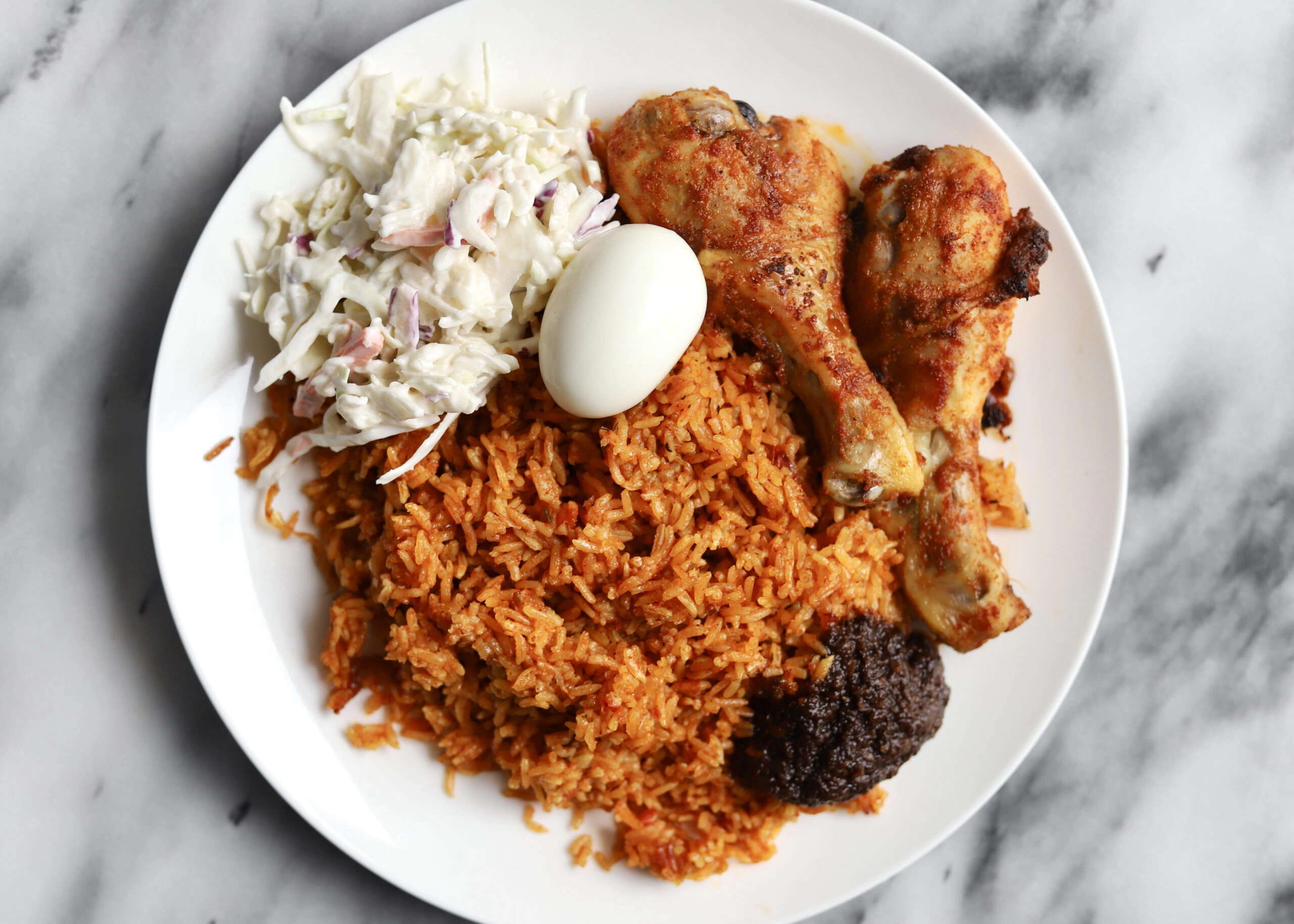 Overhead shot of Ghanaian jollof rice served with Ghana Salad, Shito, and Chicken